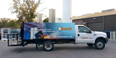 A white truck with vinyl decals parked in front of a building.