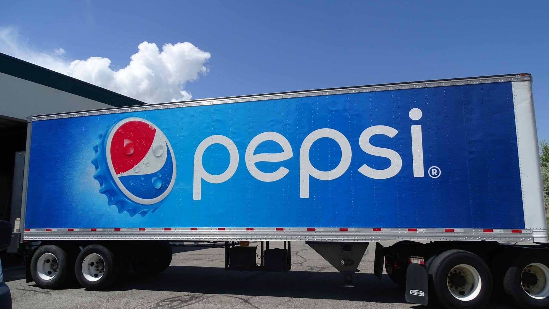 A large trailer truck featuring the Pepsi logo and branding is parked outdoors on a sunny day, ready to make deliveries to service areas.