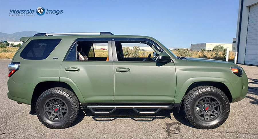 A green Toyota 4Runner with vinyl decals is parked in a parking lot.