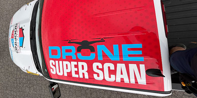 A truck with vinyl decals of the words "drone super scan" auto wrapped on its side.